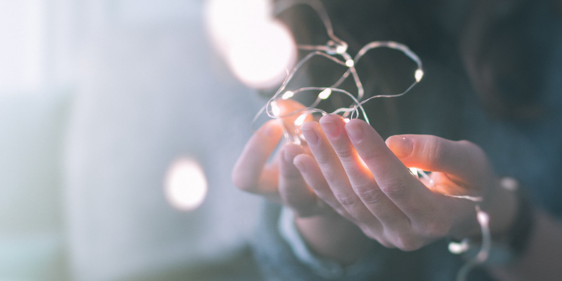 Hands holding fairy lights to represent the kindling of important stories. Norwich copywriter and content creator will make those stories shine brighter.